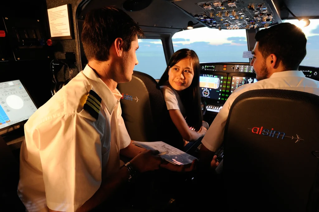 Three people in the cockpit of a flight simulator.